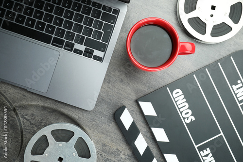 Flat lay composition with movie clapper, film reels and laptop on grey textured table