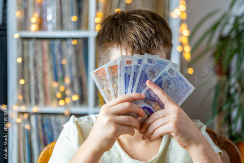 child 10 years old, primary school student presenting British GBP banknotes currency in hand, financial freedom, stealing money, adult imitation