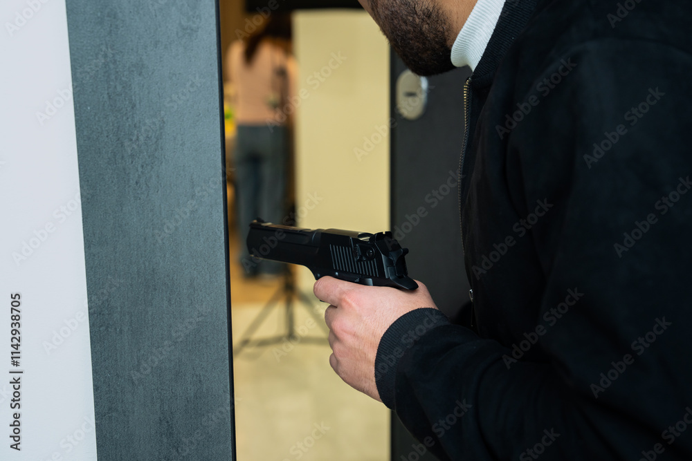 Obraz premium Attempted murder, man prepares to attack from the doorway with a gun in his hand
