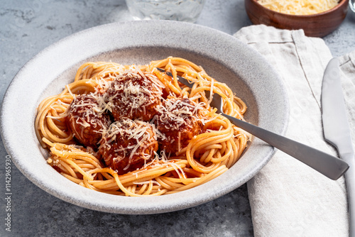 Spaghetti with meatballs, tomato sauce and parmesan on gray background