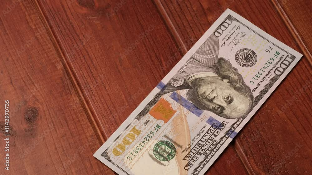 New clean US $100 bills laid out on a wooden dark table. Illustration of financial transactions using cash.