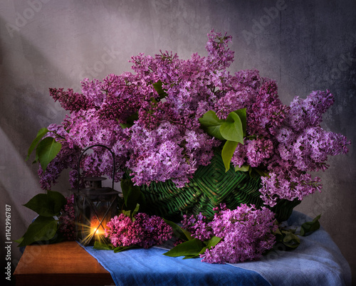 A beautiful arrangement of lilac flowers is displayed in a white vase on a table. The flowers are in full bloom and their vibrant color creates a sense of freshness and vitality.