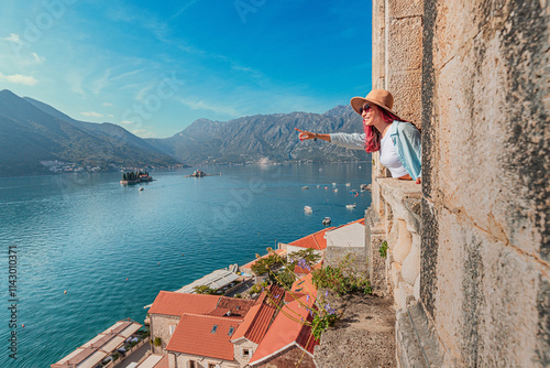 Woman pointing at the picturesque islands of Our lady of the rocks and Saint George from a high vantage point church belfry in Perast, Montenegro