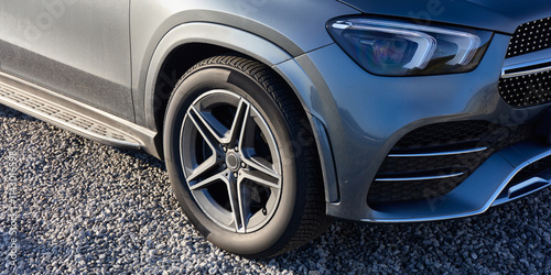 Wallpaper Mural Close-up of the wheel and front headlight of a luxury silver SUV parked in a gravel parking lot. Torontodigital.ca