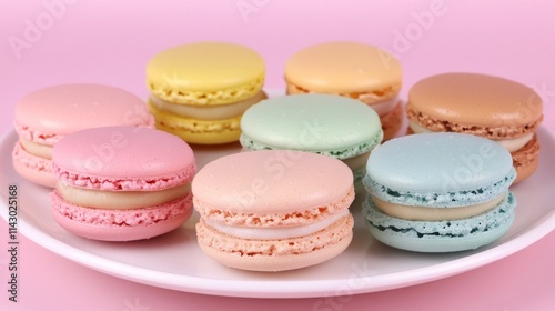 Eight pastel-colored macarons arranged on a white plate against a pink background.