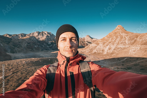 Young hiker taking a selfie with backpack in the mountains at sunset