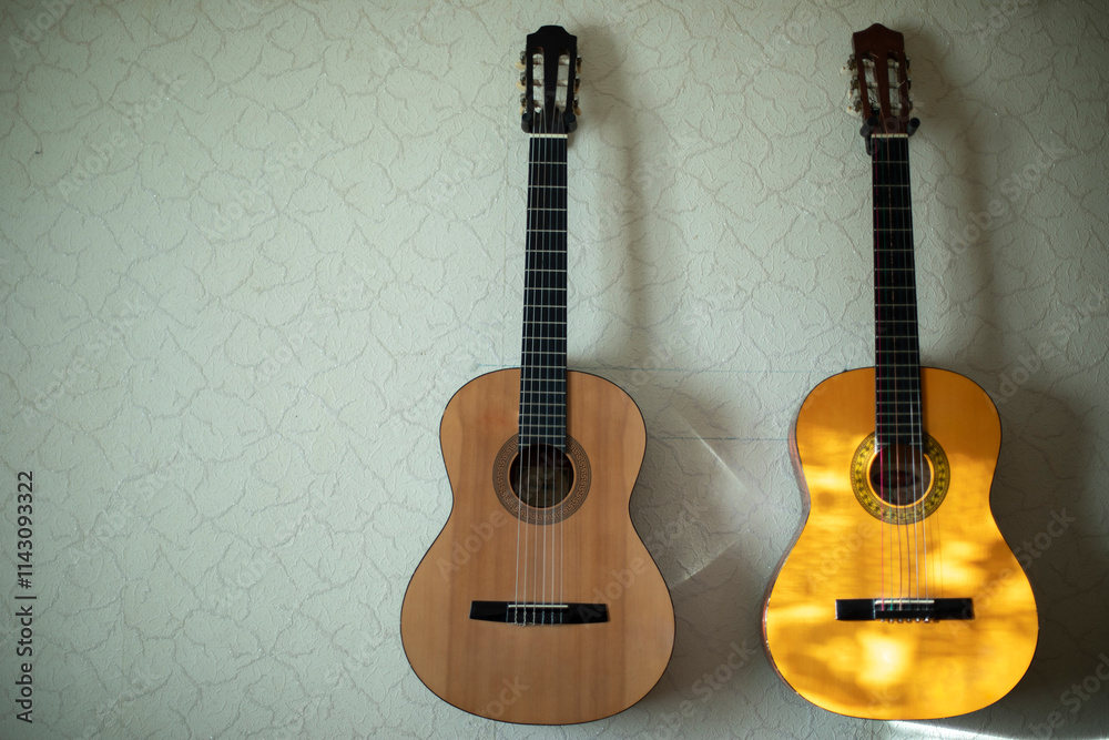 Fototapeta premium Two guitars hang on wall. Acoustic instrument. Classical guitars at home.
