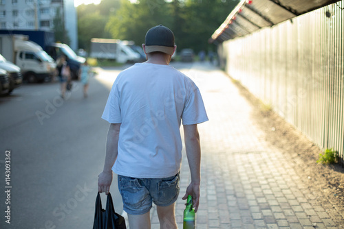 Guy walks with beer in his hand. Alcohol is harmful to health. Man walks home from store.