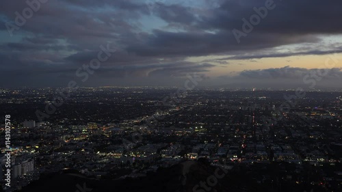 Dusk view over Los Angeles from Runyon Canyon, showcasing the city's lights under a dramatic sky filled with clouds.