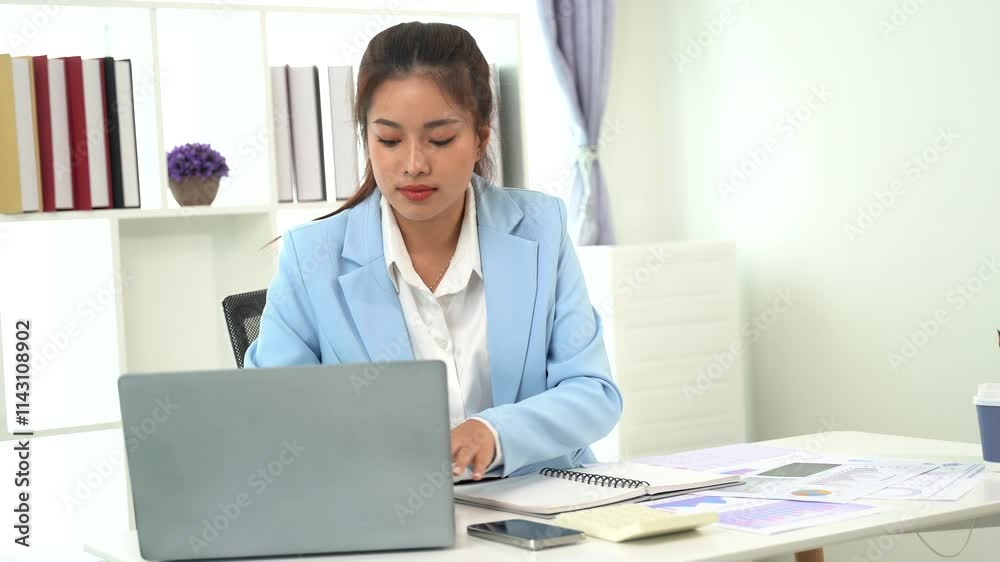 Focused on the Task: A professional woman in a blue blazer diligently works on her laptop, demonstrating a dedication to her work and a commitment to success. Focused on the Task: A professional woman in a blue blazer diligently works on her laptop, demonstrating a dedication to her work and a commitment to success.