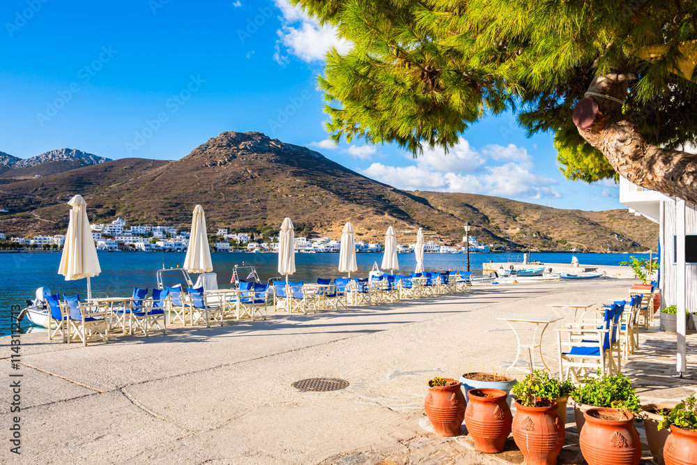 Cafe tables with sun umbrellas on beach in Katapola port, Amorgos island, Cyclades, Greece