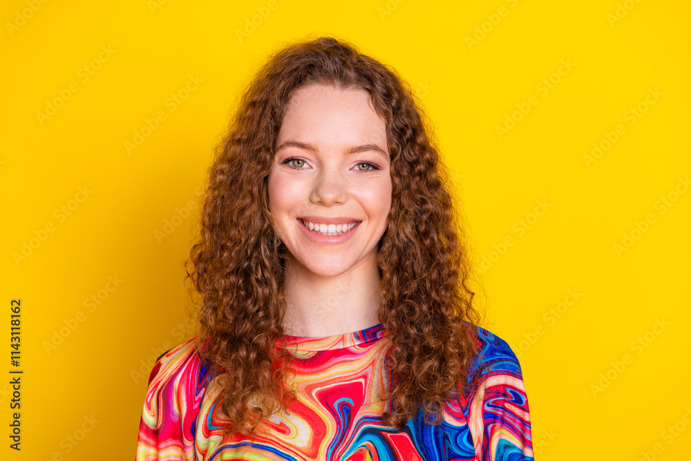 Φωτογραφία Charming young woman with curly red hair and stylish attire in front of a vibrant yellow background, exuding happiness and joy