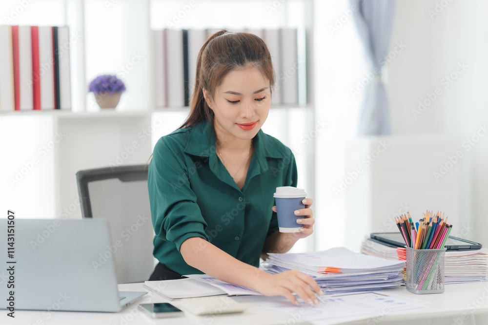 Focused and Ready: A determined businesswoman in a green blouse, meticulously working through paperwork at her desk, showcasing a sense of dedication and a clear focus on tasks. Focused and Ready: A determined businesswoman in a green blouse, meticulously working through paperwork at her desk, showcasing a sense of dedication and a clear focus on tasks.