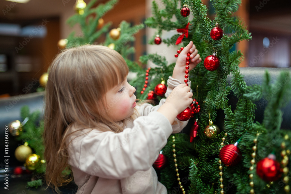 A young child carefully decorates a Christmas tree with red ornaments and festive beads. The holiday scene captures the joy of childhood and the magic of preparing for Christmas in a cozy indoor A young child carefully decorates a Christmas tree with red ornaments and festive beads. The holiday scene captures the joy of childhood and the magic of preparing for Christmas in a cozy indoor