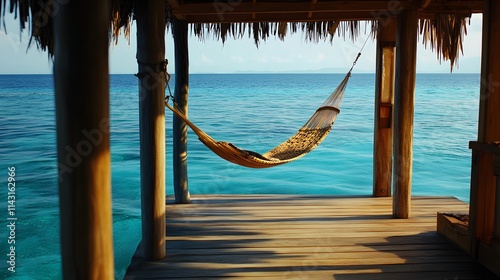 A cozy wooden ocean villa with a hammock strung between pillars floating peacefully in calm blue waters.