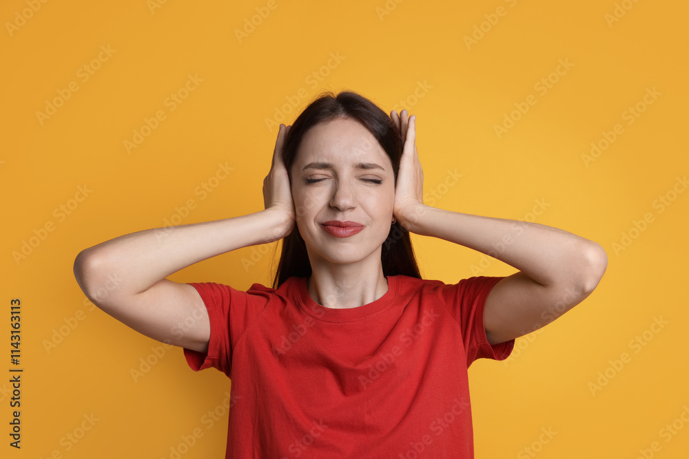 Woman covering her ears on orange background Woman covering her ears on orange background