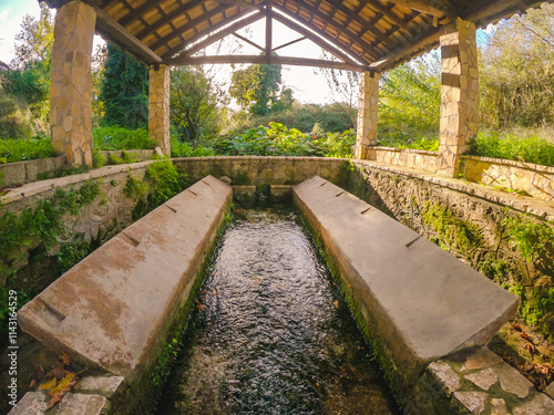 Old wash house with running water under a wooden roof. photo