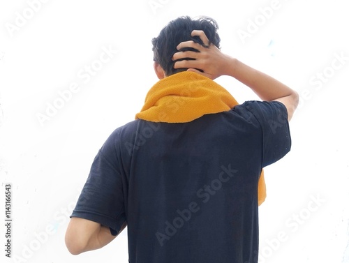 Rear view of teenage Asian man scratching his head and carrying a towel around his neck. photo