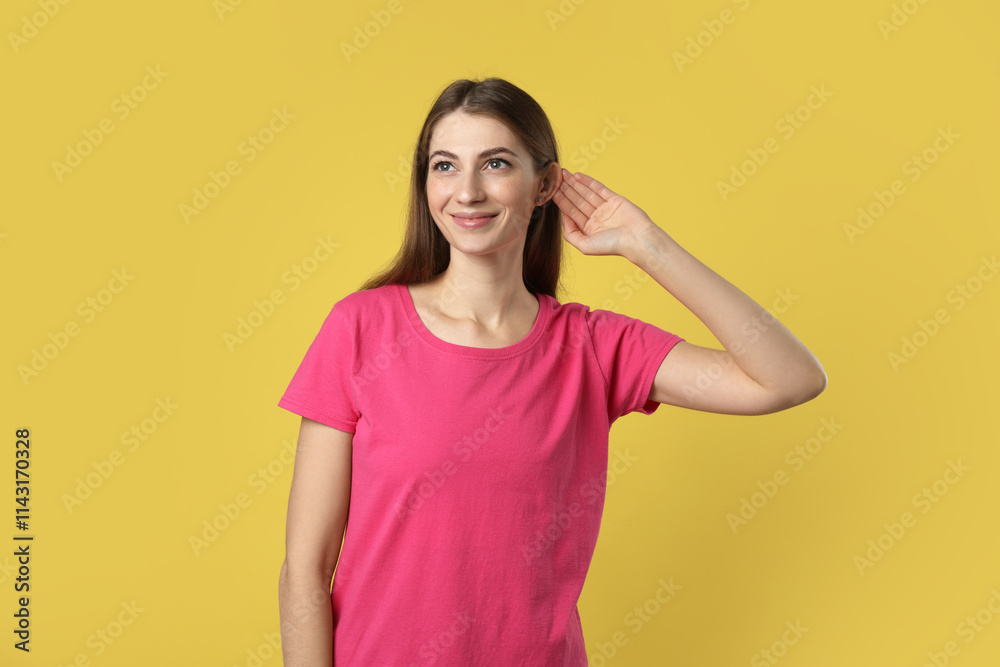 Woman showing hand to ear gesture on dark yellow background Woman showing hand to ear gesture on dark yellow background