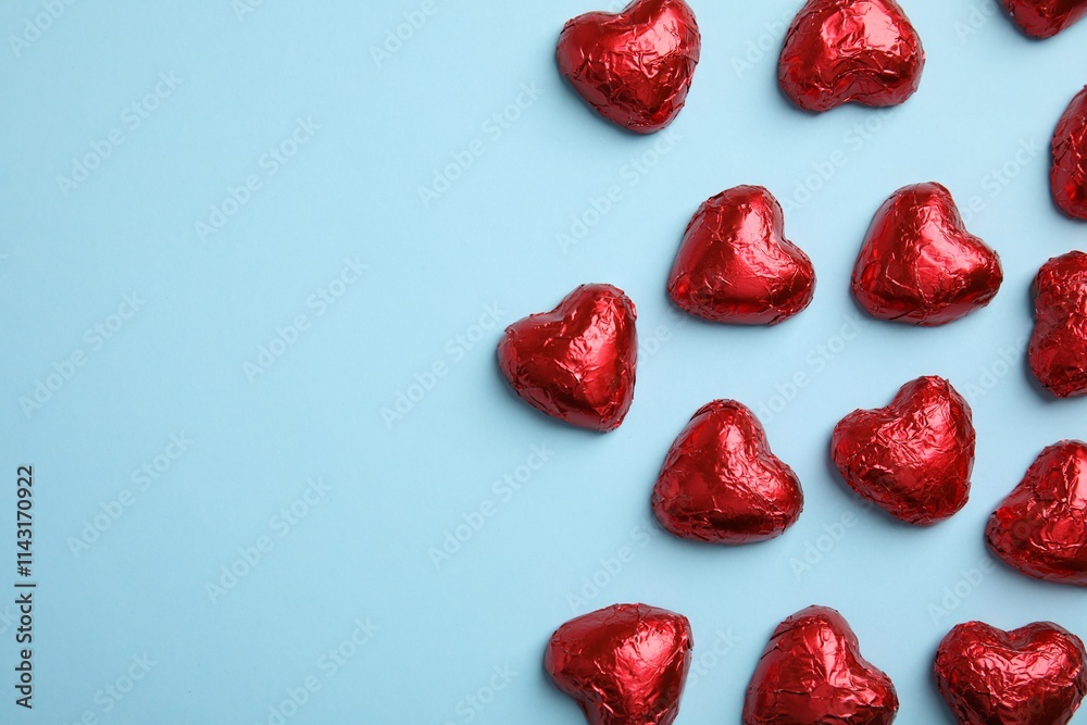 Heart shaped chocolate candies on light blue background, flat lay with space for text. Valentine's day treat Heart shaped chocolate candies on light blue background, flat lay with space for text. Valentine's day treat