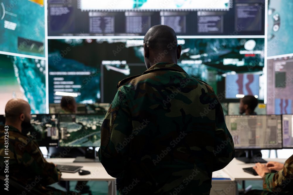 Fototapeta premium Infantry unit trooper collecting intelligence for a field operation, working with high tech reconnaissance gear and a big screen. Military staff analyzes real time data, surveillance support.