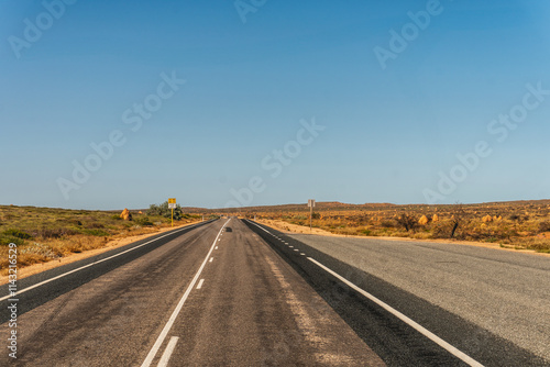 Australien road in the Outback with trees on the Roadside
