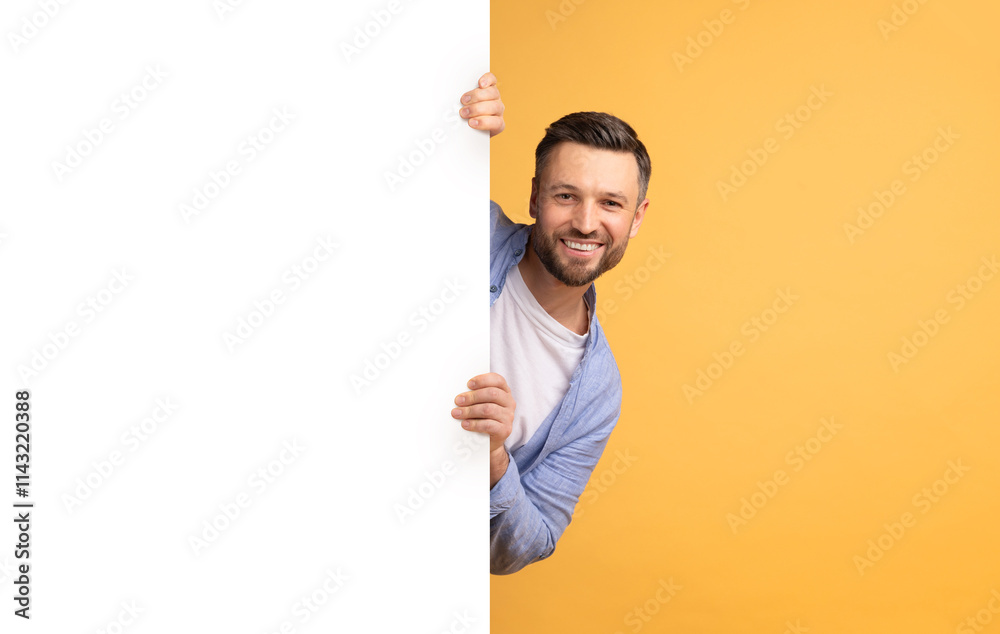 A cheerful Caucasian father is playfully looking around a blank white panel, showcasing affection and joy. The vibrant yellow background creates a fun and lively atmosphere.