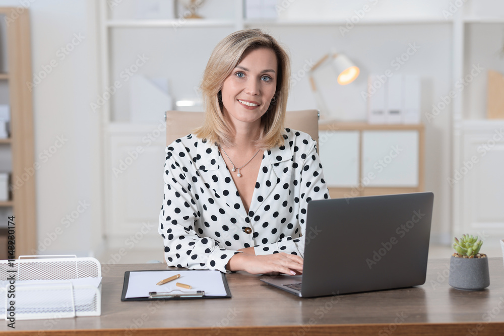 Businesswoman working on laptop at table in office Businesswoman working on laptop at table in office