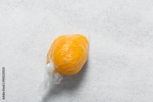 Overhead view of nigerian starch wrapped in cellophane on a white countertop, top view of nigerian starch swallow on a white plate