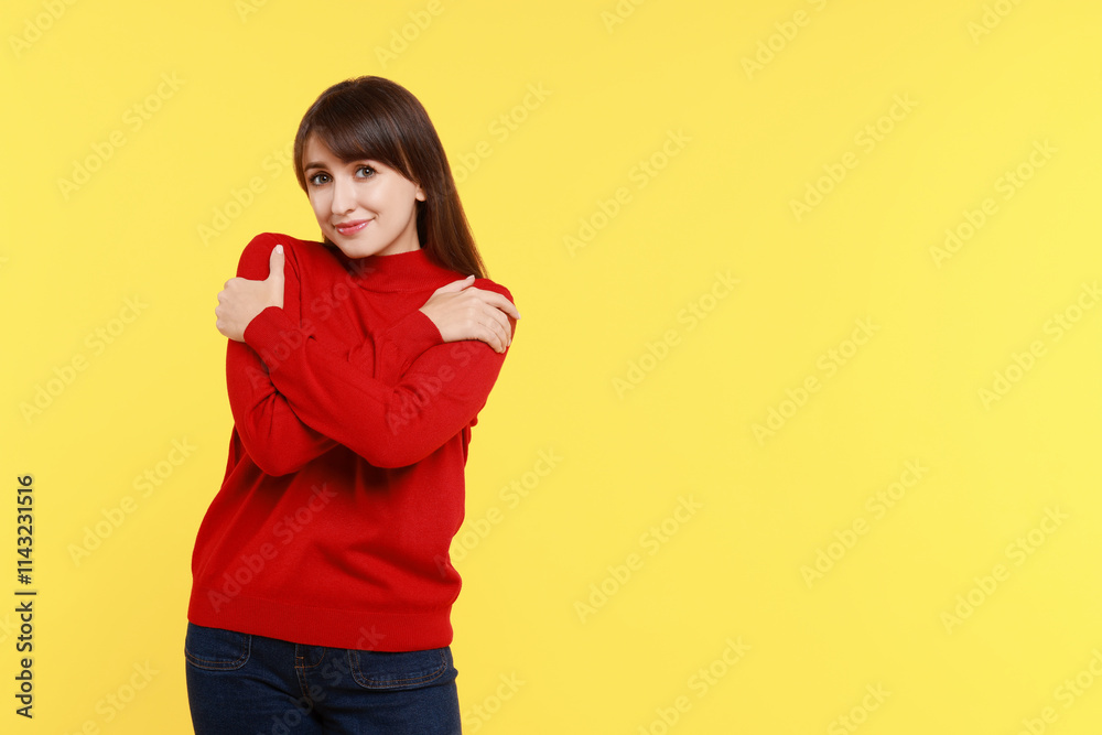 Young woman hugging himself on yellow background, space for text Young woman hugging himself on yellow background, space for text