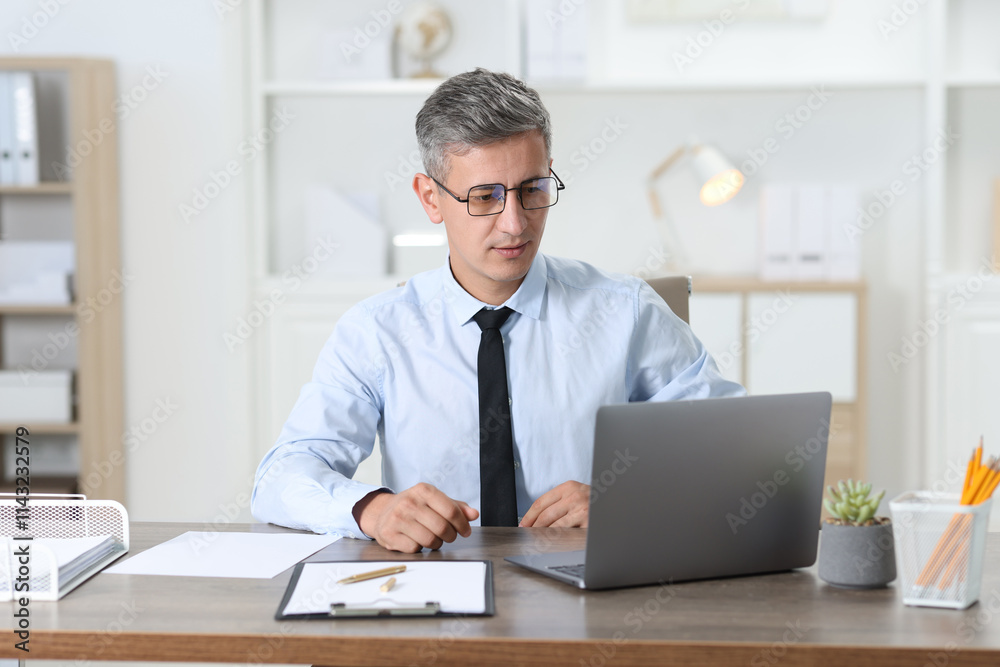 Businessman working with laptop at table in office Businessman working with laptop at table in office