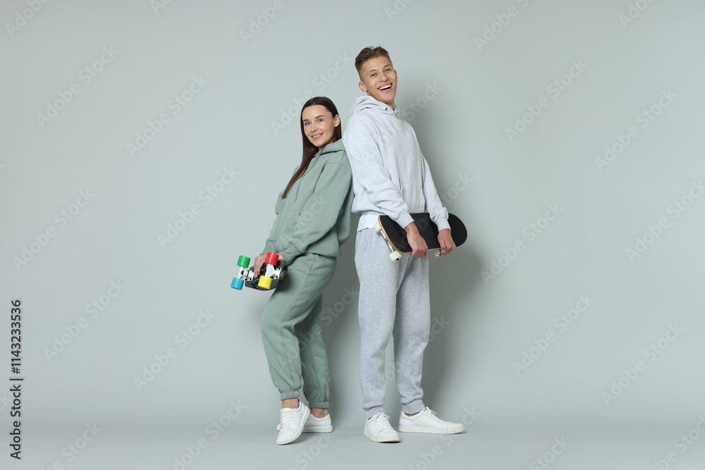 Fototapeta premium Happy friends with skateboards on light grey background