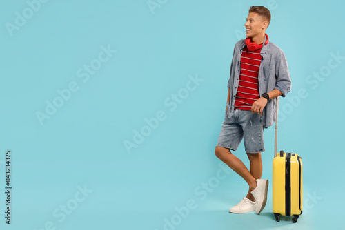 Happy traveller with suitcase on light blue background, space for text