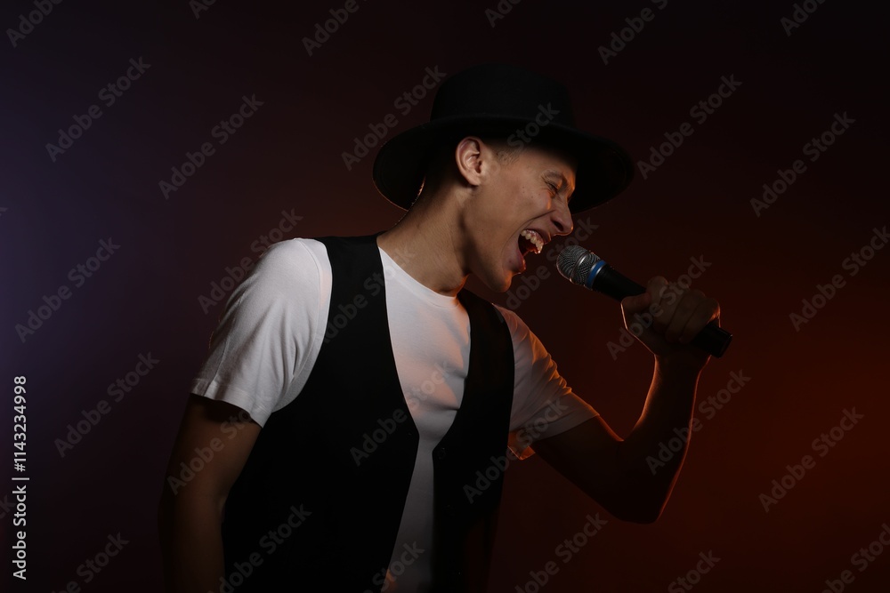 Talented young man singing on dark background with color light Talented young man singing on dark background with color light
