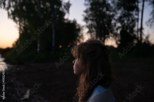 Contemplative girl at dusk by a serene lakeside forest photo