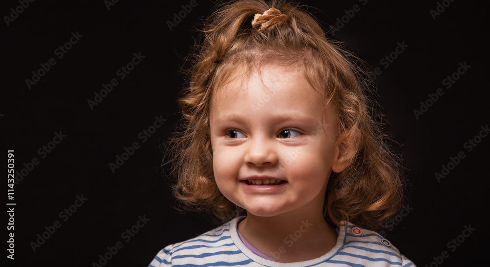 Smiling enjoying happy baby girl looking with positive emotion with curly hair on black studio background with empty copy space. Closeup facial expression portrait Smiling enjoying happy baby girl looking with positive emotion with curly hair on black studio background with empty copy space. Closeup facial expression portrait