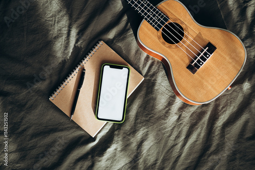 Ukulele, notebook, and smartphone on fabric surface photo