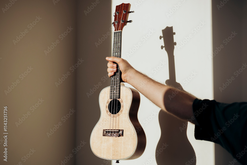 Ukulele Held in Hand with Shadow on Wall in Natural Light Ukulele Held in Hand with Shadow on Wall in Natural Light