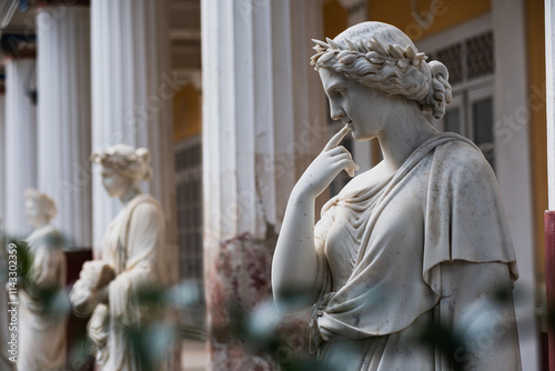 Antique statues of Women in Wreaths. The white stone statues stand in a neat row among Greek-style columns