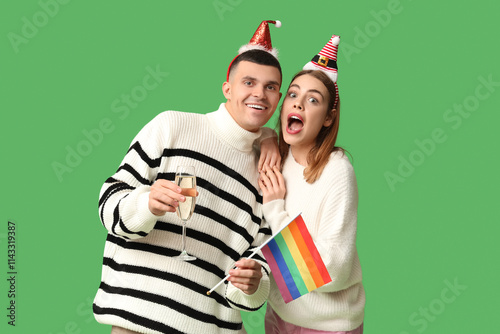 Wallpaper Mural Young couple in Santa hats with LGBT flag and champagne on green background Torontodigital.ca