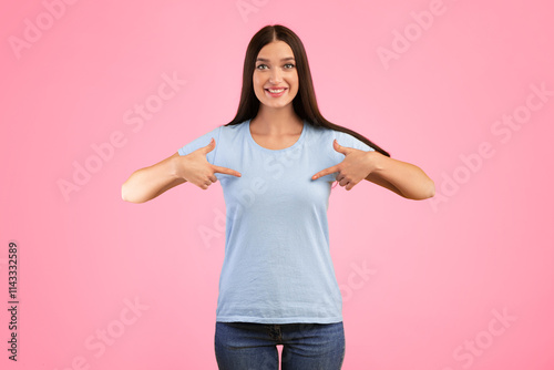 Choose Me. Portrait of positive female model pointing at herself, wearing blue t-shirt for your text or promotional content, indicating chest, advertising concept, lady isolated over yellow background