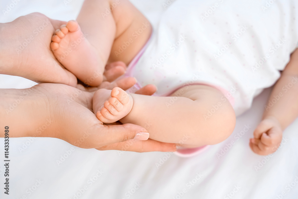 Mother holding her little baby's legs in bedroom, closeup Mother holding her little baby's legs in bedroom, closeup