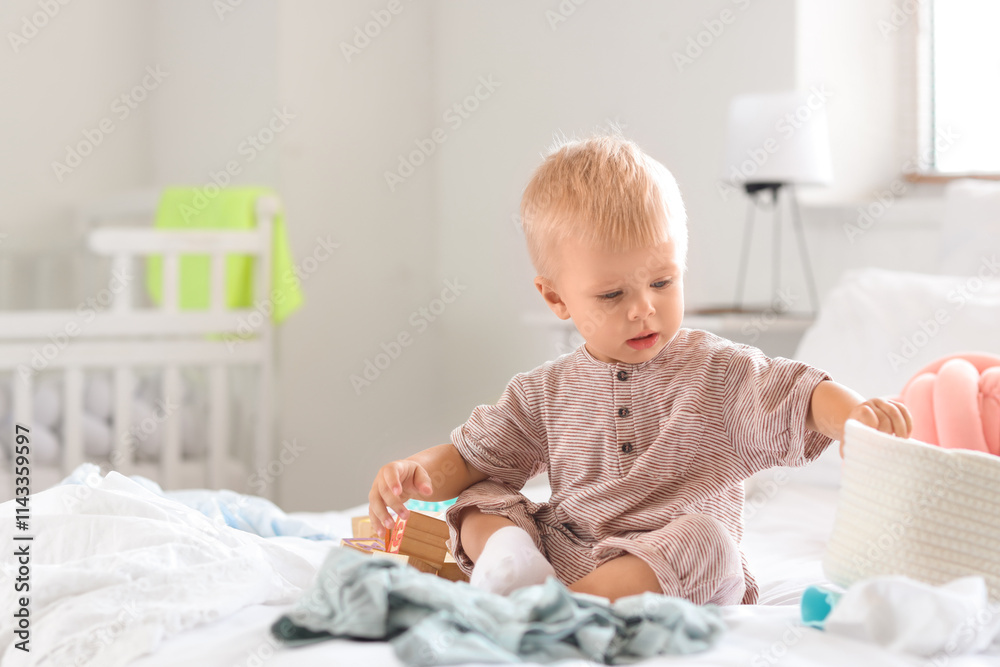 Naughty baby boy with basket sitting in messy bedroom Naughty baby boy with basket sitting in messy bedroom