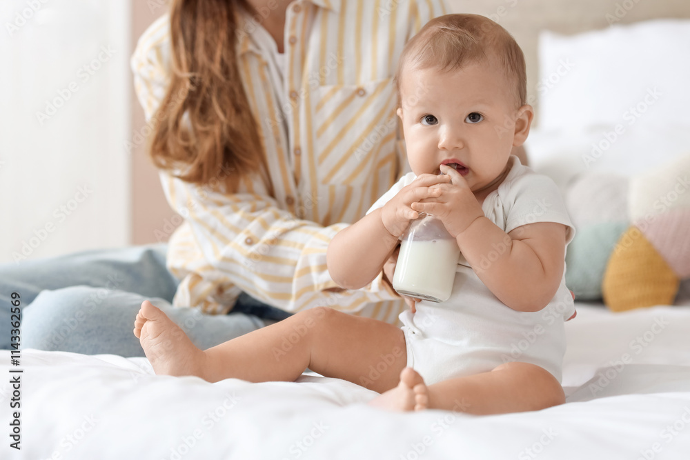 Mother feeding her little baby with milk from bottle in bedroom, closeup Mother feeding her little baby with milk from bottle in bedroom, closeup
