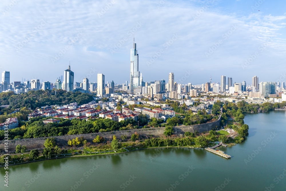 Fototapeta premium Aerial view showcasing the vibrant autumn colors of Xuanwu Lake and the skyline of Nanjing under a clear sky
