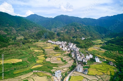 Breathtaking aerial view of rural Wuyuan countryside showcasing terraced fields and quaint village life under blue skies photo