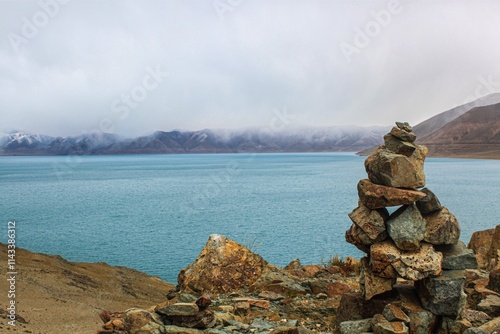 Scenic view of Dangjak Yumtso lake in Tibet with rock cairn under cloudy skies photo