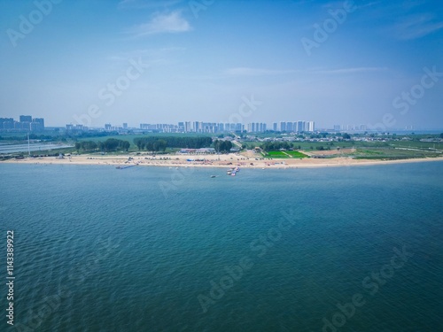 Bohai Bay Dongdaihe summer seaside scenery features clear waters and sandy beaches near modern cityscape photo