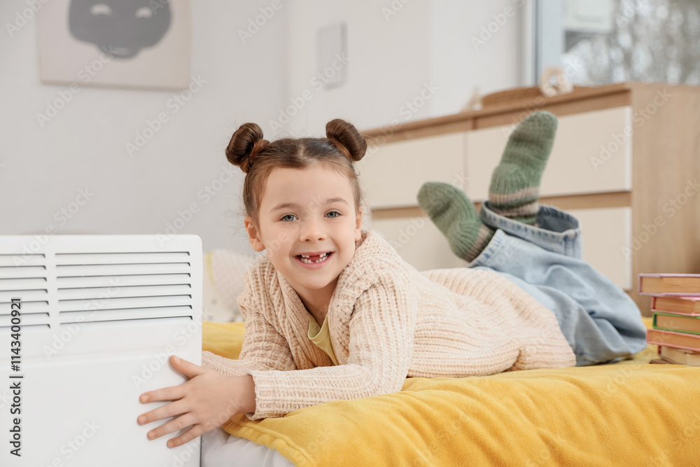 Little girl lying near electric convector heater in bedroom Little girl lying near electric convector heater in bedroom