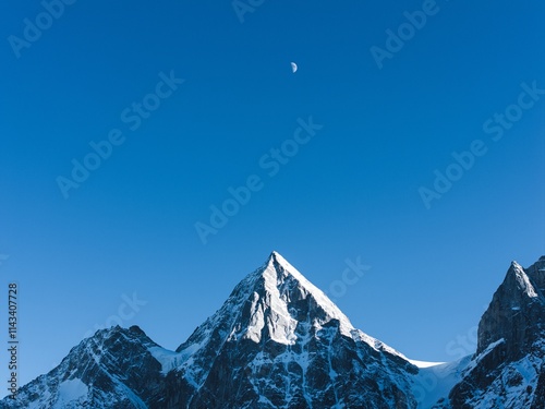 Bipenggou winter landscape showcasing majestic snowy mountains and a clear blue sky with a hint of the moon photo